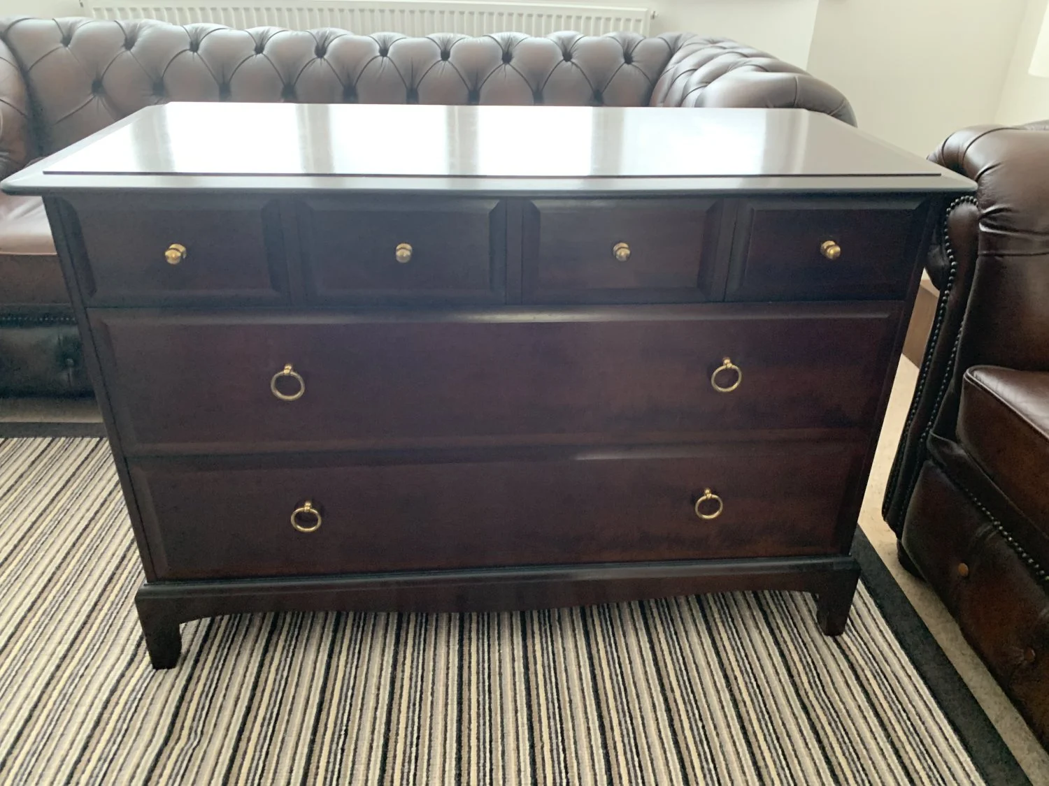 Dark mahogany-toned chest of drawers with brass ring handles