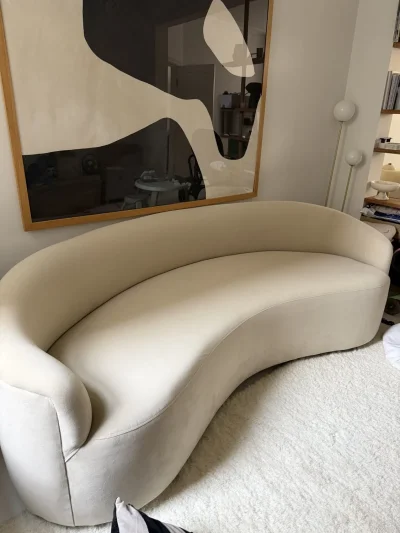 Large beige curved upholstered sofa with wraparound back on Furnish Well