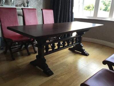 Vintage dark wood trestle dining table with 6 red leather backed chairs on Furnish Well