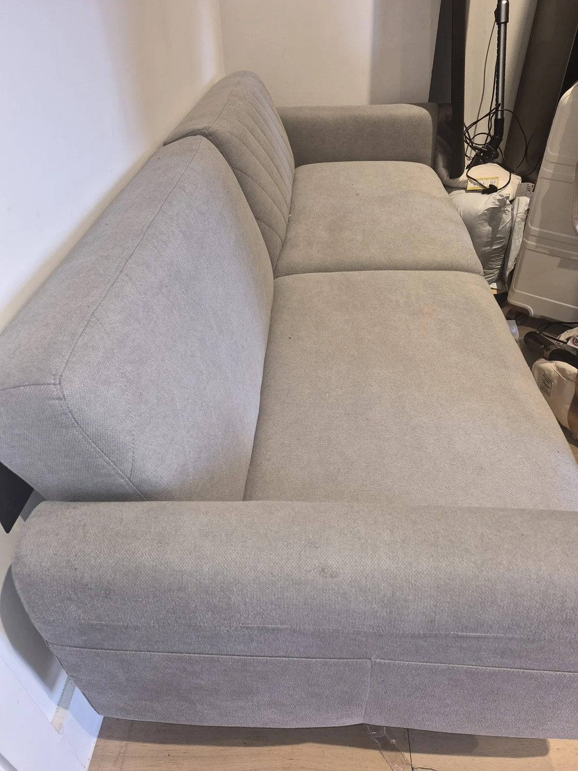 Modern three-seat grey fabric sofa bed with stitched back cushions